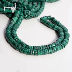 two strands of green glass beads on a white surface