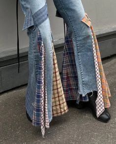 the legs of a person wearing jeans and boots with ties on them, standing in front of a wall