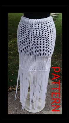 a white crocheted skirt with tassels on the bottom is shown in front of grass