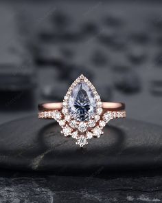 an engagement ring with a pear shaped blue diamond surrounded by smaller round diamonds on top