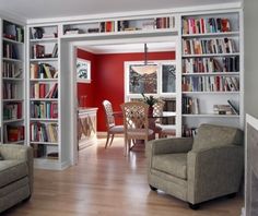 a living room filled with lots of furniture and bookshelves covered in red walls