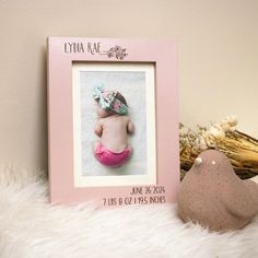 a pink frame with a baby's photo on it next to a stuffed animal