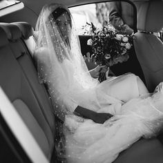 a bride sitting in the back seat of a car