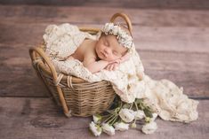 a newborn baby sleeping in a basket with flowers on the floor next to it's head