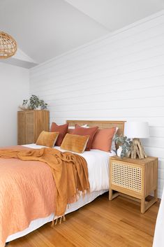 a bedroom with wood floors and white walls, has an orange blanket on the bed