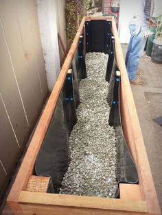 a long wooden boat filled with rocks and gravel