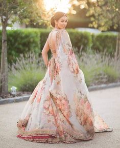 a woman in a floral dress standing on the street with her back to the camera