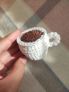 a small crocheted cup is held in someone's hand