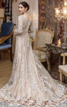 a woman in a wedding dress is standing near a couch and chair with her back turned to the camera