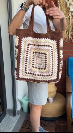 a woman holding a brown and white crocheted bag