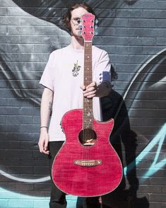 a man standing in front of a wall with a guitar on it's neck