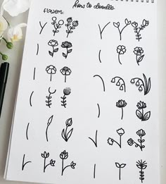 a notebook with flowers drawn on it next to a pen and flower arrangement in the background