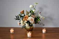 a vase filled with lots of flowers sitting on top of a table next to candles