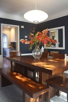 a dining room table with two benches and a vase filled with flowers on top of it