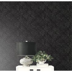 a lamp on top of a white dresser next to a black wallpapered wall