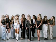 a group of beautiful women standing next to each other in front of a white wall