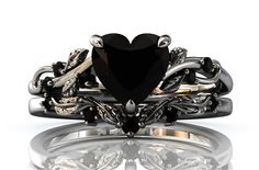 a heart shaped black diamond sits on top of a silver ring with intricate designs and chains