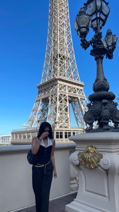 a woman standing in front of the eiffel tower with her cell phone up to her ear