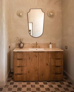 a bathroom vanity with a large mirror above it and checkered flooring on the ground