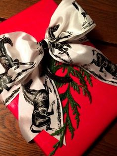 a present wrapped in red and white ribbon with an animal print bow on the top