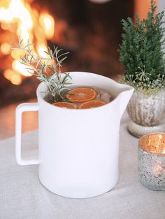 a pitcher filled with liquid sitting on top of a table next to a potted plant