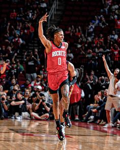 a basketball player is running on the court with his arms in the air as he celebrates