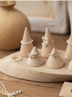 small wooden cones with pearls on them sitting on a table next to a beaded necklace