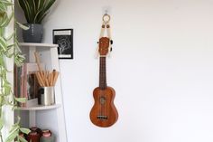 a ukulele hanging on the wall next to a potted plant