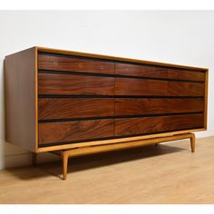 a wooden dresser sitting on top of a hard wood floor next to a white wall