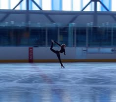 a woman skating on an ice rink with her arms in the air while wearing black