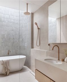 a white bath tub sitting next to a bathroom sink under a shower faucet