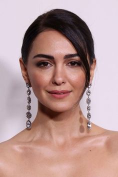 an image of a beautiful woman with earrings on her head and wearing a strapless dress