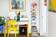 there is a yellow chair in front of a desk with books and magazines on it