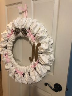 a wreath made out of diapers with the letter m on it is hanging on a door