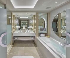 a large bathroom with two sinks, mirrors and bathtub in the middle of it