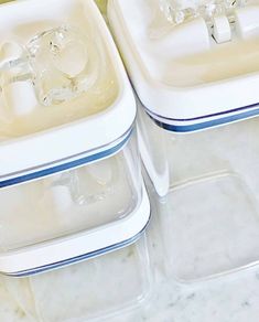 three plastic containers with clear lids sitting on top of a marble countertop next to each other