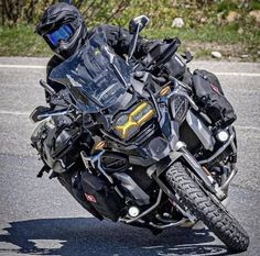 a man riding on the back of a black motorcycle down a curvy road