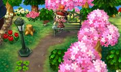 an animal crossing game with pink flowers in the foreground and a person sitting on a park bench