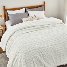 a bed with white comforter and pillows in a bedroom