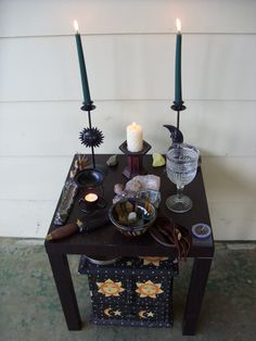 a table with candles and other items on it in front of a house or building