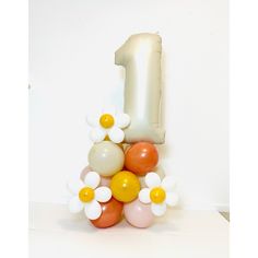 the number one balloon is made up of balloons and daisies in white, orange, and yellow