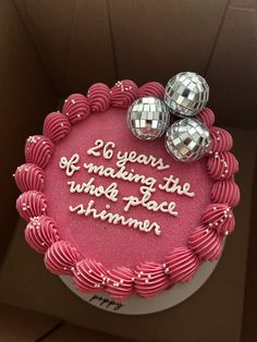 a birthday cake decorated with pink icing and two disco balls on top that says, 20 years of making the who's place shame