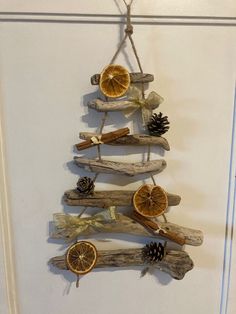 a christmas tree made out of driftwood with orange slices and pine cones hanging from it