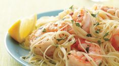 a plate of pasta with shrimp and lemon wedges