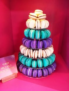 a stack of colorful macaroons sitting on top of a pink shelf next to a book