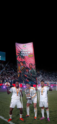 three soccer players holding up their trophies on the field