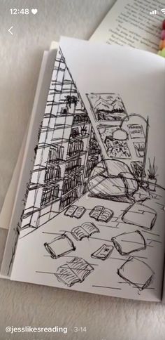 an open book with drawings on it and some other things in the background, including bookshelves