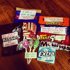 several candy bars on a wooden table with some sayings written on the bags next to them