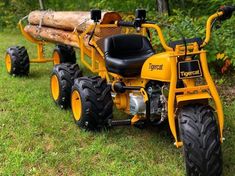 a yellow tractor parked in the grass next to a log