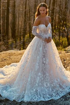 a woman in a wedding dress standing on top of a rock with trees in the background